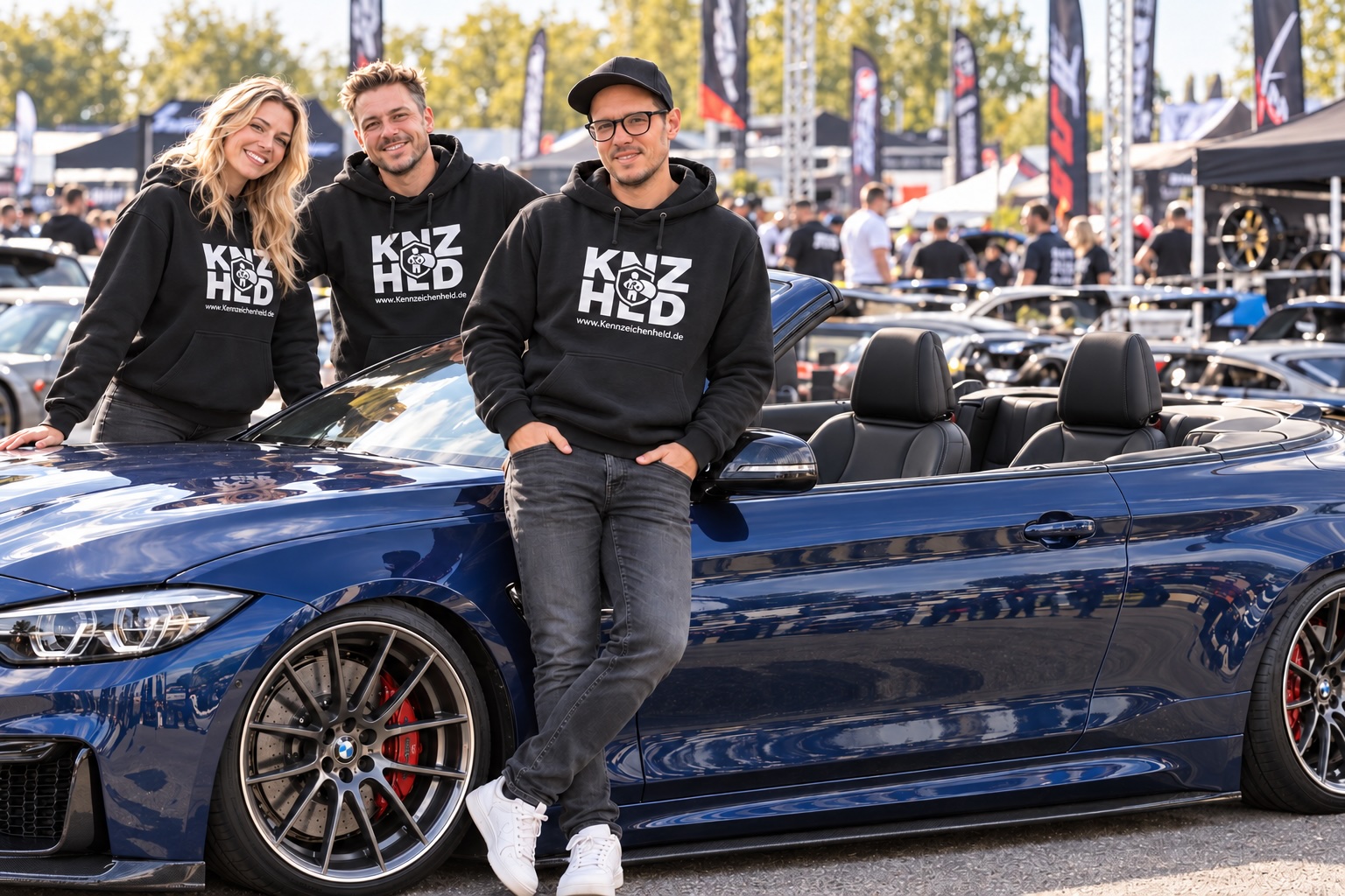 Drei Personen in Kennzeichenheld-Hoodies neben einem blauen Cabrio auf einem Tuning-Event